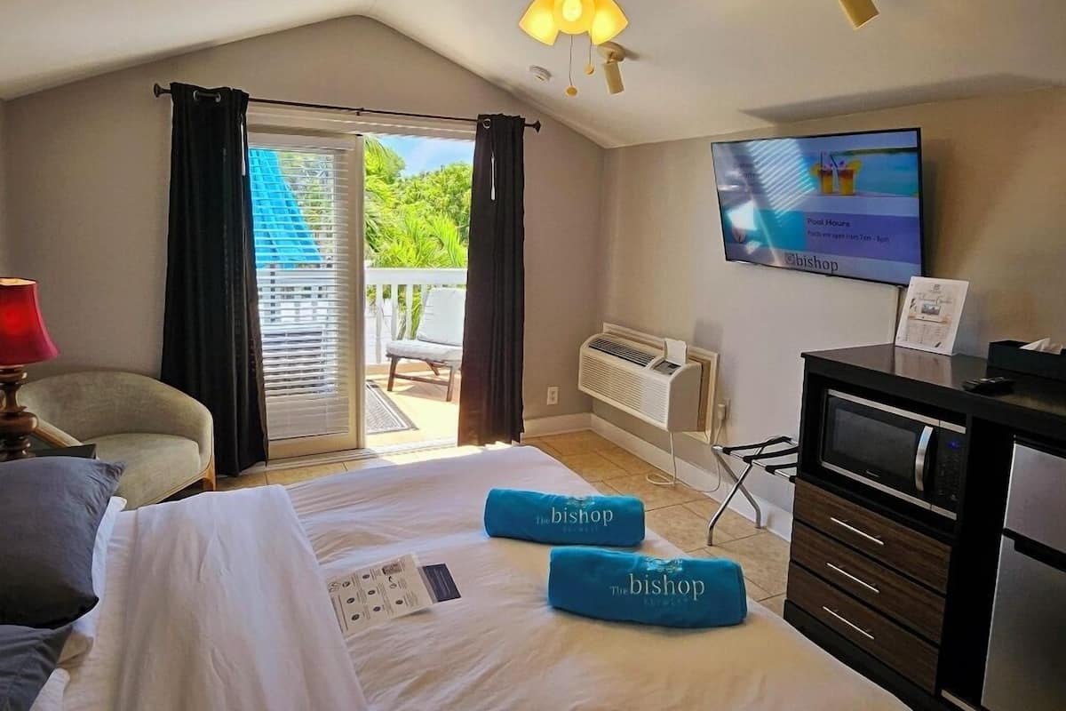 A hotel room with a bed, a desk, a television, and a view of the outdoors.