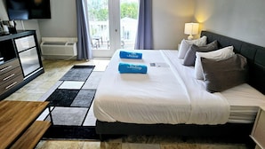 A hotel room with a bed, a desk, a television, and a view of the outdoors through a sliding door. - Bishop Hotel Key West (Key West)
