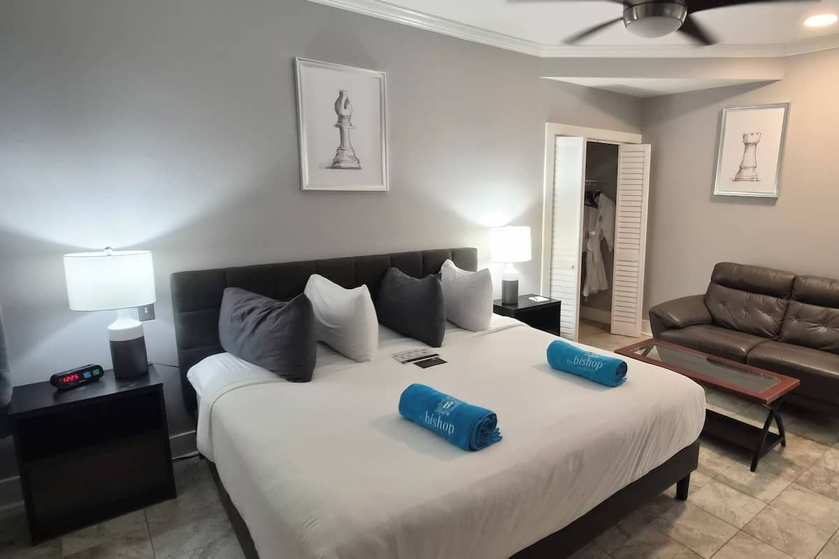 A hotel room with a bed, a nightstand, a desk, a chair, and a ceiling fan.