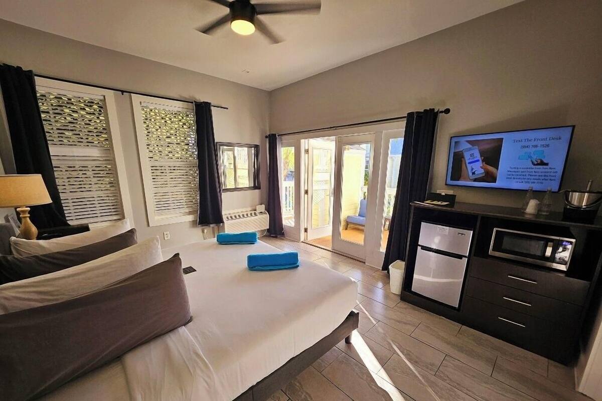 A hotel room with a bed, a desk, a television, and a view of the outdoors.