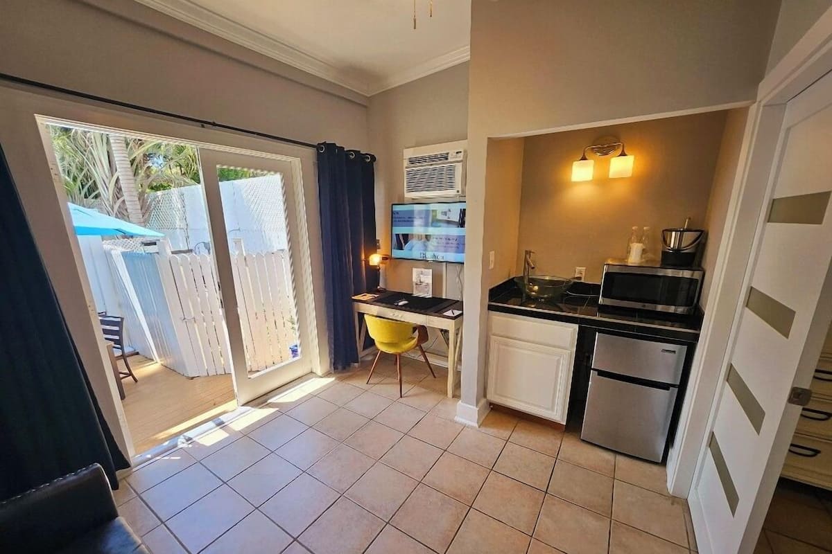 A compact kitchen with a dining area, a refrigerator, a microwave, and a sink.