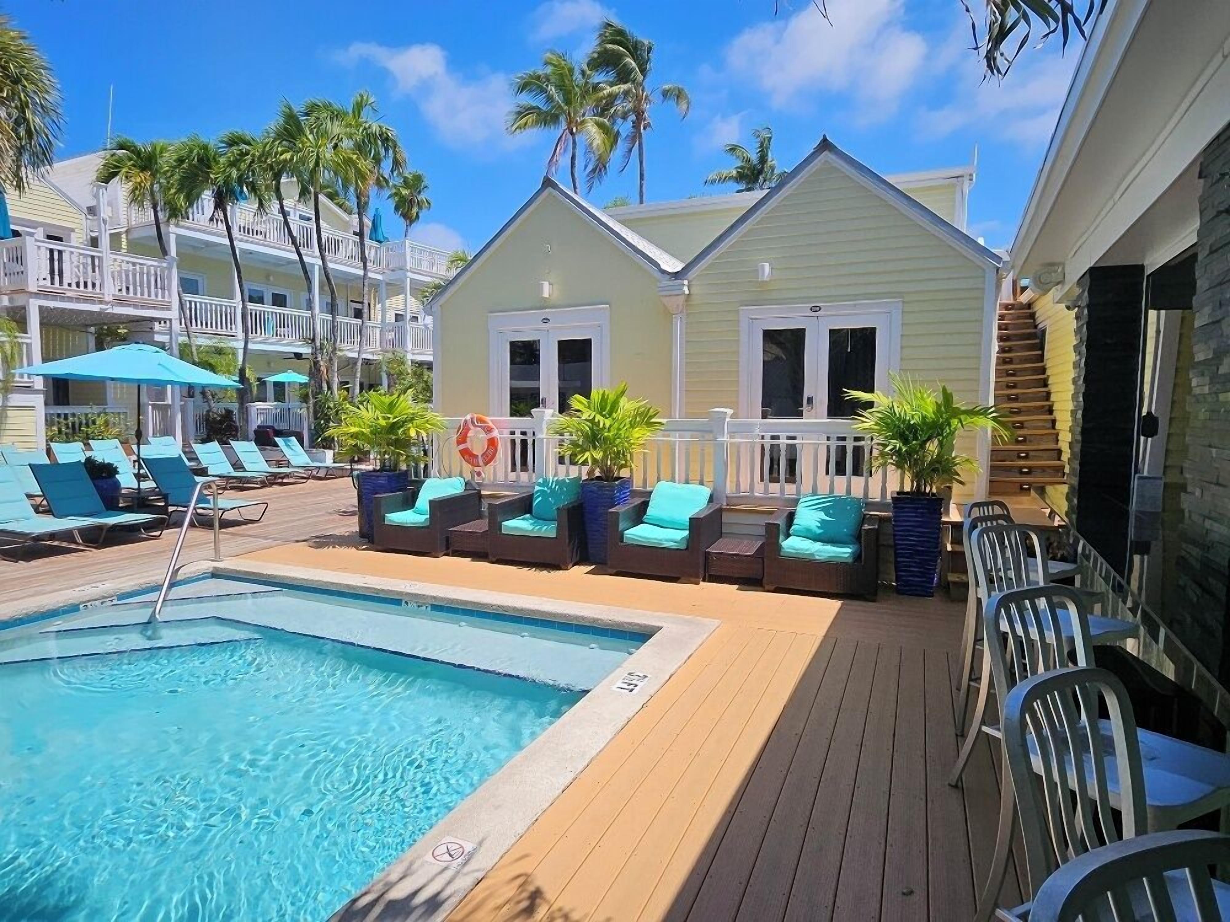 Un espace piscine comprenant des chaises longues, une petite piscine et un bâtiment doté d’un balcon.