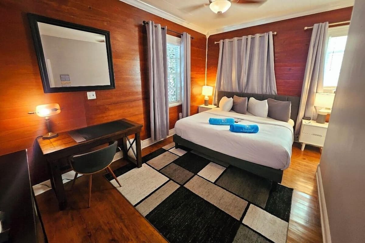 A hotel room with a bed, desk, chair, and a ceiling fan.