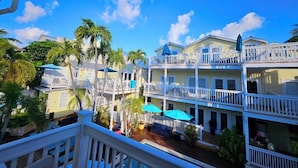 A multi-story hotel with balconies, outdoor seating, and palm trees. - Bishop Hotel Key West (Key West)