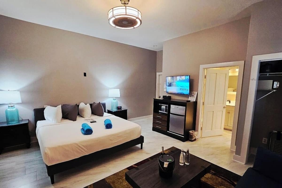A hotel room with a bed, bedside lamps, a television, a desk, and a coffee table.