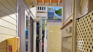 A narrow wooden pathway leading to a door, a fire alarm box, and a lattice fence. - Bishop Hotel Key West (Key West)
