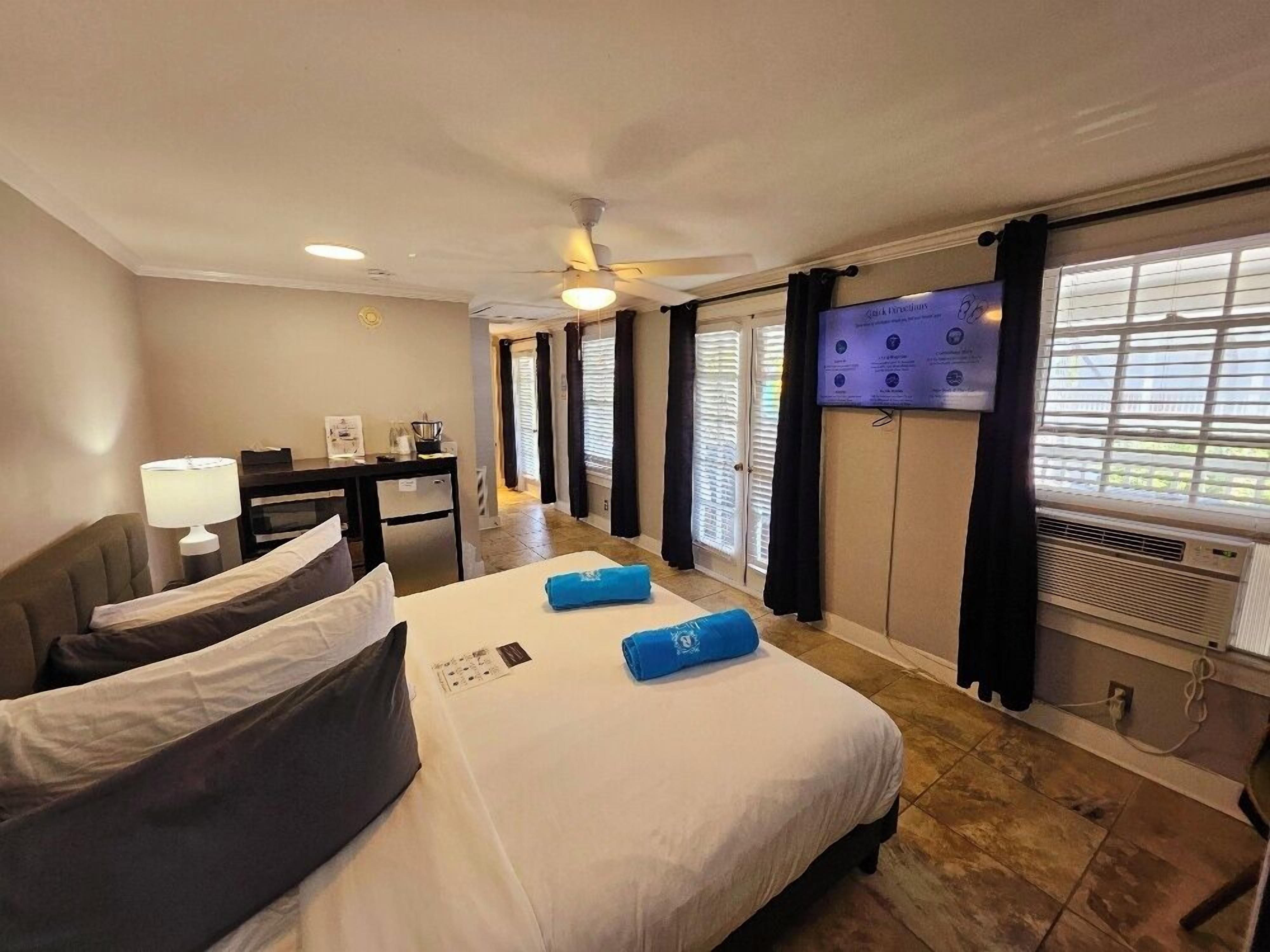 A hotel room with a bed, desk, and TV.