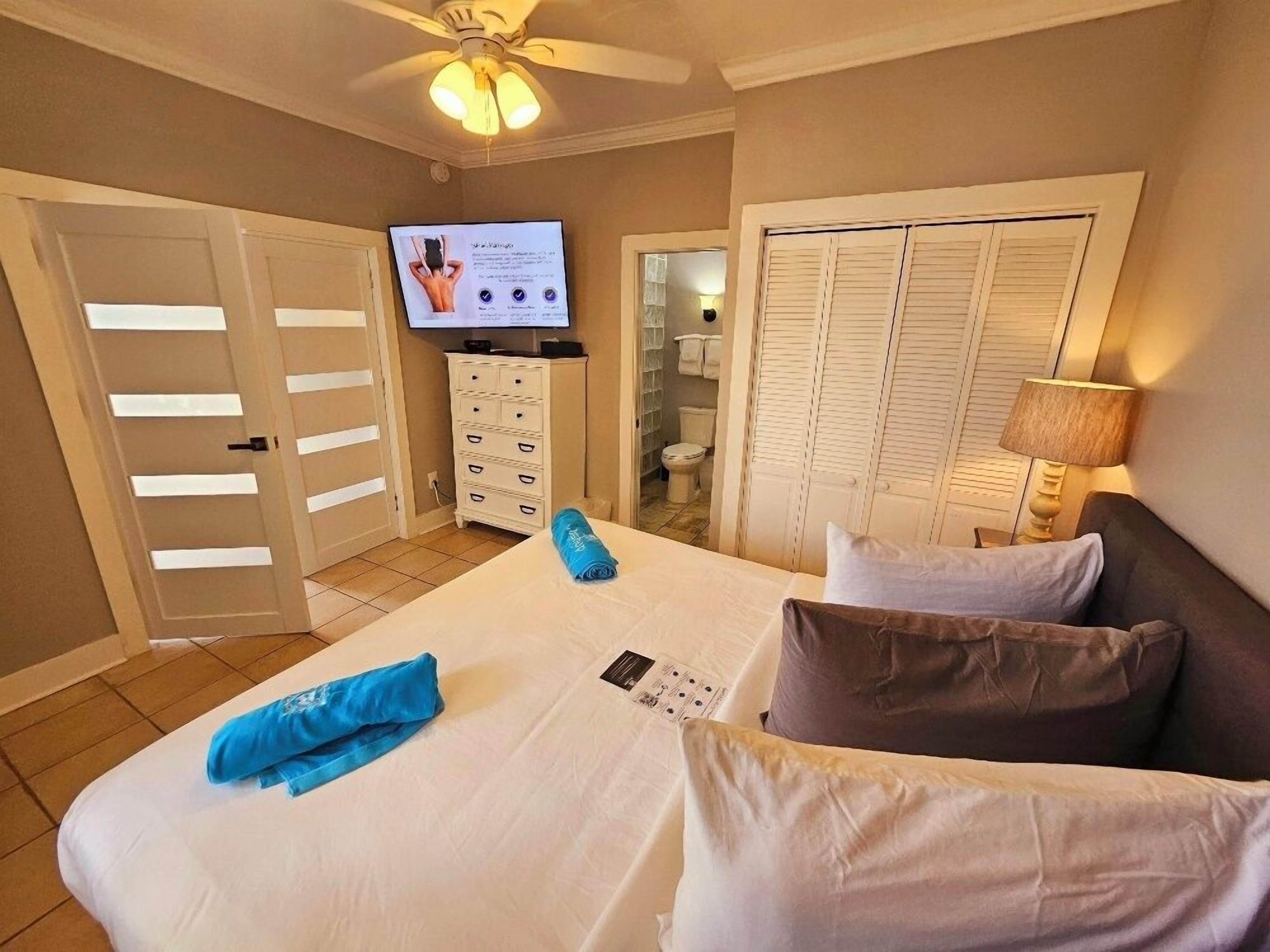 Une chambre d’hôtel avec un lit, une télévision, une commode et une salle de bain visible à travers une porte ouverte.
