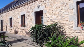A stone building with multiple windows and a small outdoor seating area.