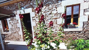 A stone building with a window displaying red flowers.