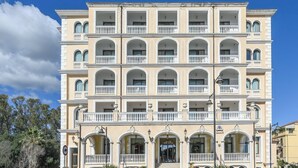Un hotel de varios pisos con fachada simétrica, balcones y una entrada central.