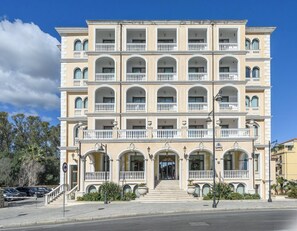 A multi-story hotel with a symmetrical facade, balconies, and a central entrance with steps. - Hotiday Olbia Porto (Olbia)