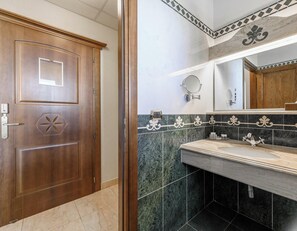 A bathroom with a wooden door, a sink with a mirror, and decorative tiles. - Hotiday Olbia Porto (Olbia)