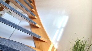 A wooden staircase with carpeted steps and a potted plant at the bottom. - Zauberhaft Übernachten am EP (Ettenheim)