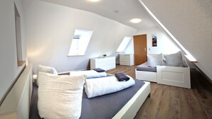 A modern loft bedroom with a sloped ceiling, built-in white furniture, and a skylight. - Zauberhaft Übernachten am EP (Ettenheim)