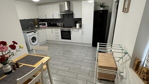 A modern kitchen with white cabinets, a microwave, a washing machine, and a drying rack. - Apartment - Sleeps 2 - Parking - Wifi (Colchester)