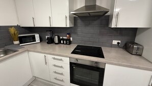 A modern kitchen with white cabinets, a black stove, a microwave, a toaster, and a coffee maker. - Apartment - Sleeps 2 - Parking - Wifi (Colchester)