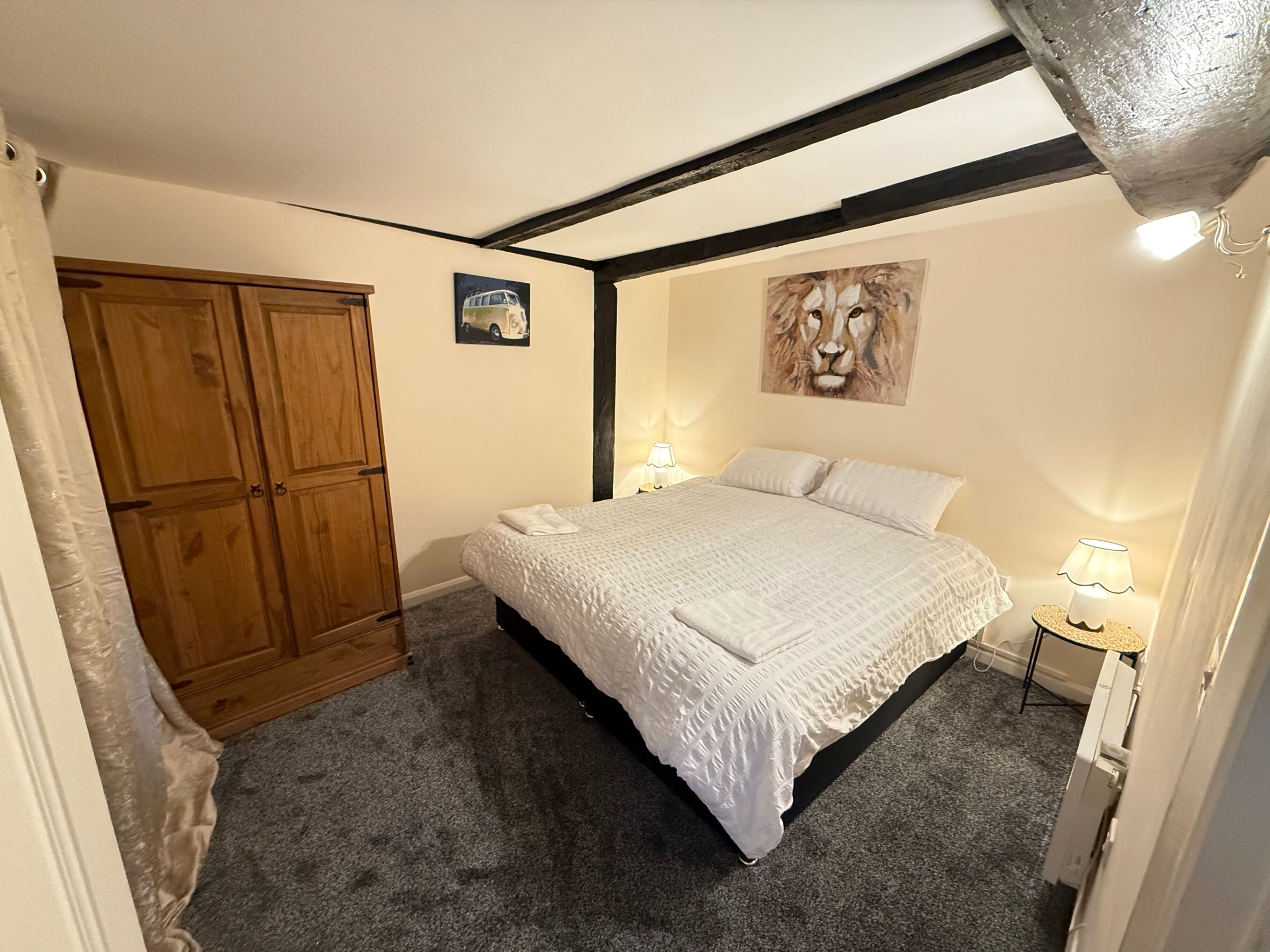 Une chambre à coucher avec un lit, une armoire en bois, un tableau et une table de chevet avec une lampe.