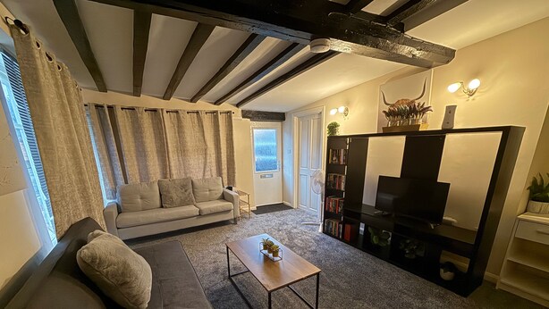 A living room with a sofa, coffee table, and a bookshelf. - Apartment - Sleeps 2 - Parking - Wifi (Colchester)