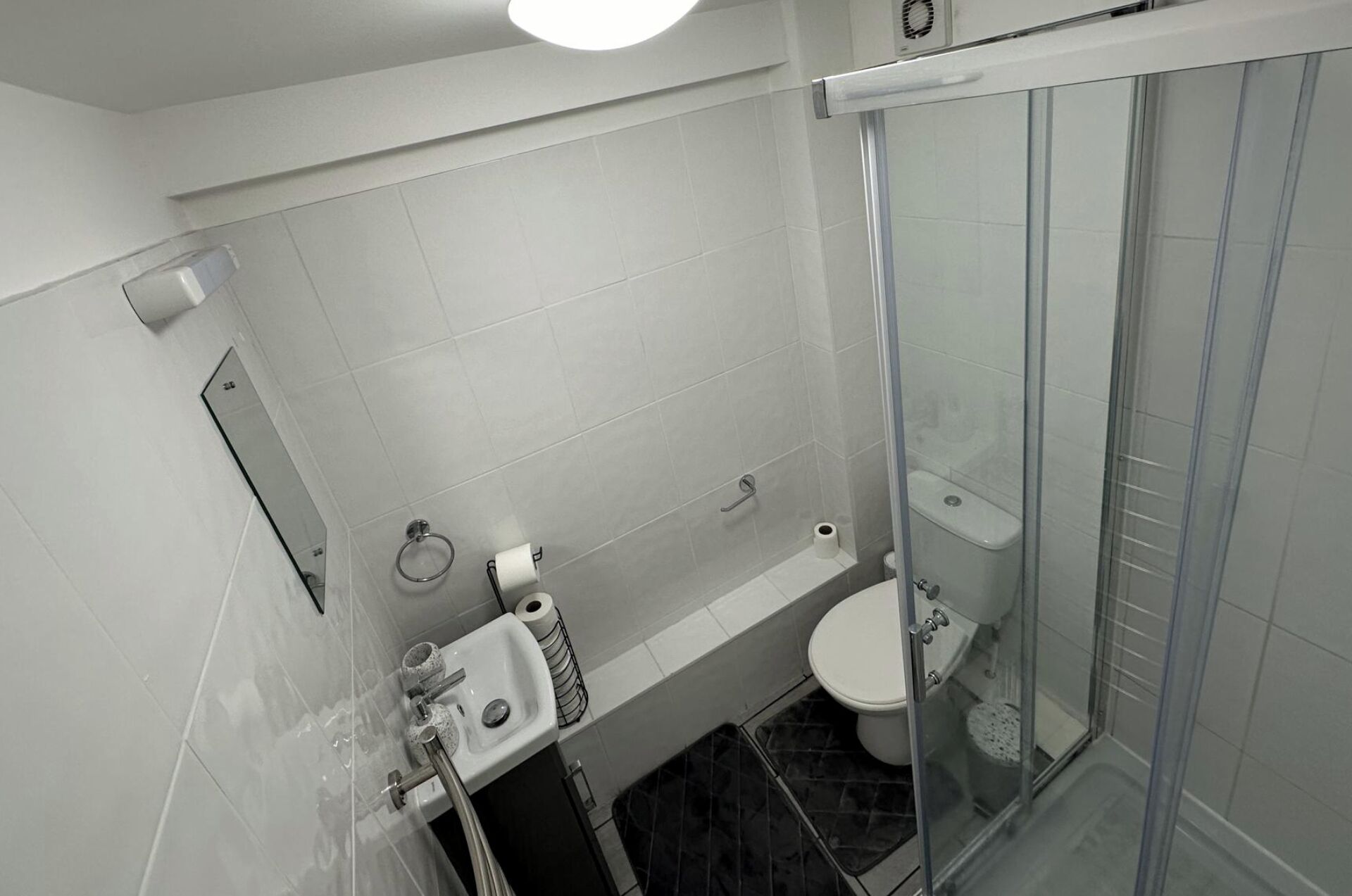 A modern bathroom with a glass-enclosed shower, a toilet, and a sink.
