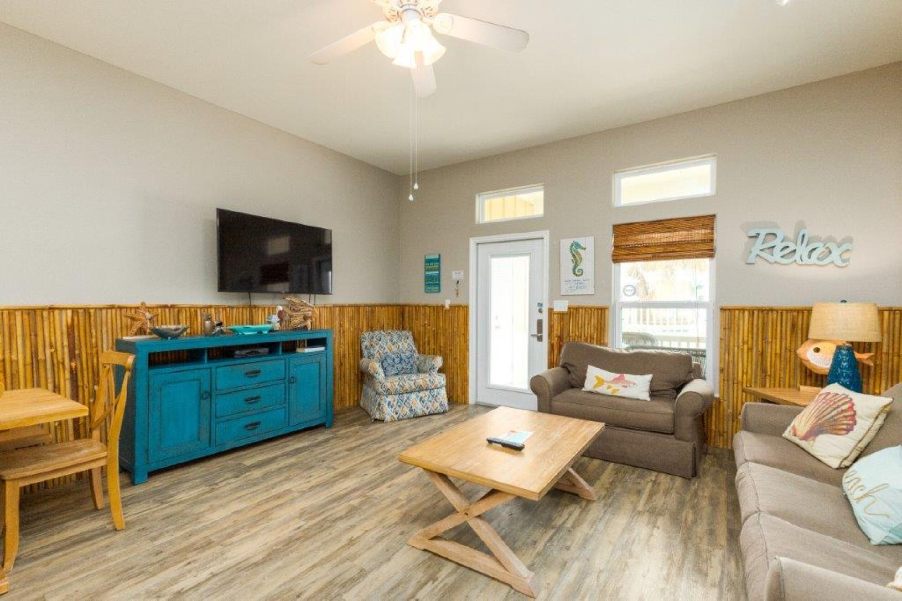 A living room with a television, a blue cabinet, a wooden coffee table, a brown sofa, and a chair.