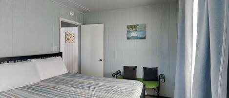 Une chambre à coucher avec un lit, un bureau, une chaise et un tableau accroché au mur.
