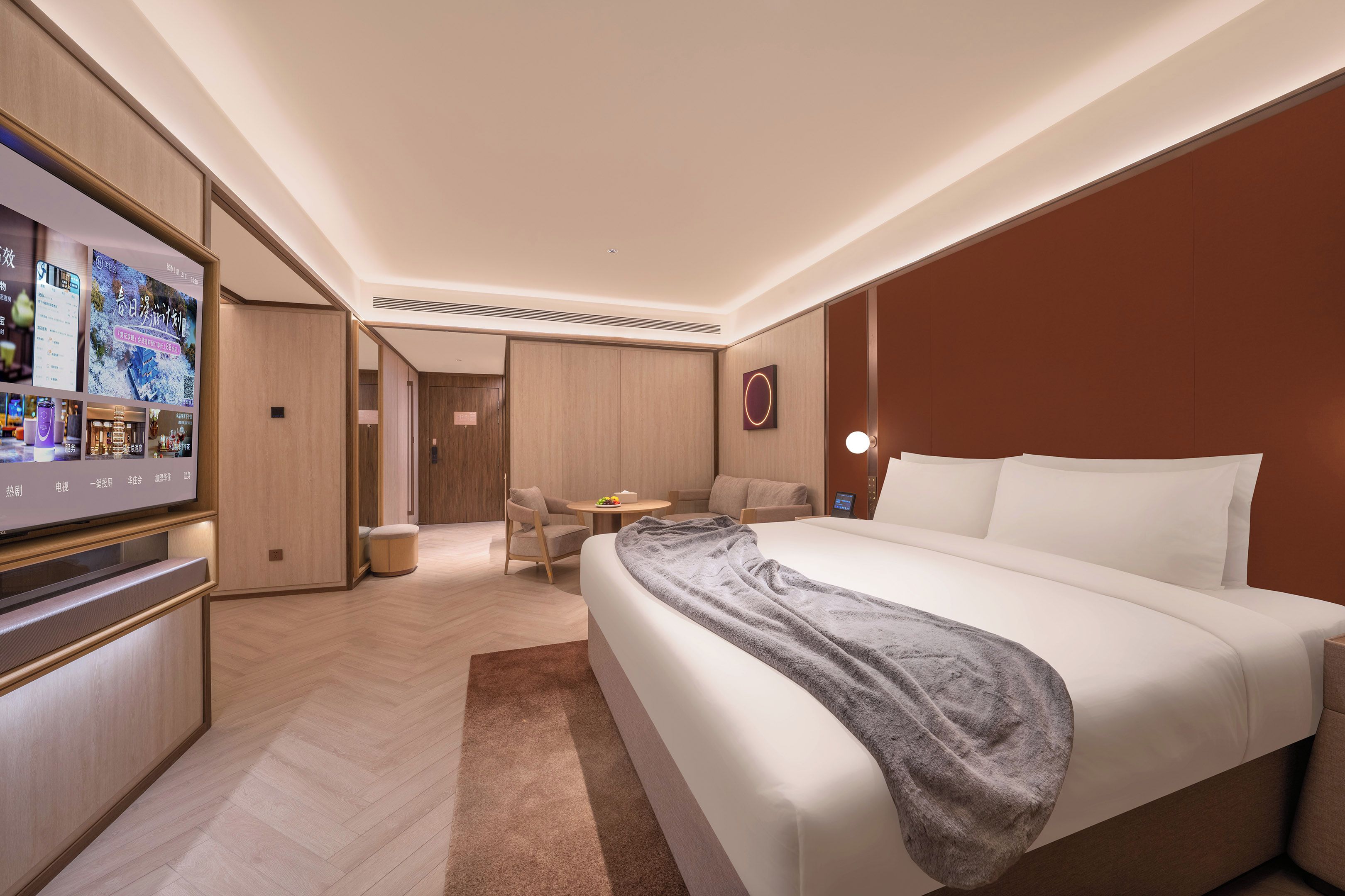 Une chambre d’hôtel moderne dotée d’un grand lit, d’une télévision, d’un coin salon et d’un mur revêtu de panneaux en bois.