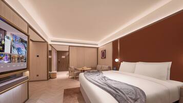 Une chambre d’hôtel moderne dotée d’un grand lit, d’une télévision, d’un coin salon et d’un mur revêtu de panneaux en bois.