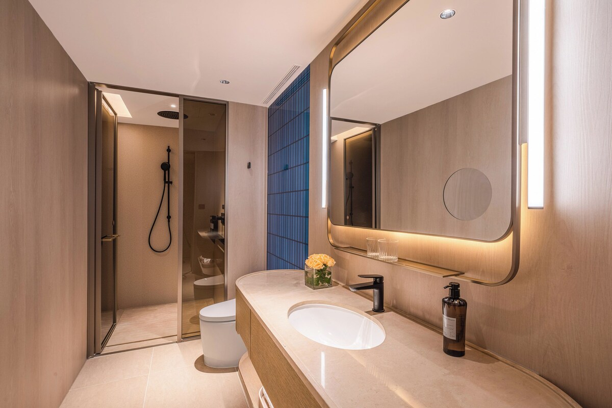 Un baño moderno con ducha de vidrio, un lavabo blanco y un espejo grande.