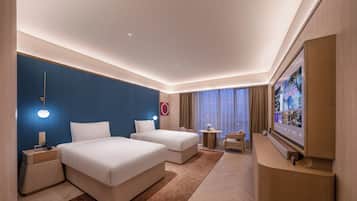 Habitación de hotel con dos camas, un televisor, una mesita y una silla.