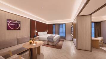A modern hotel room with a bed, sofa, and a small table with a lamp.