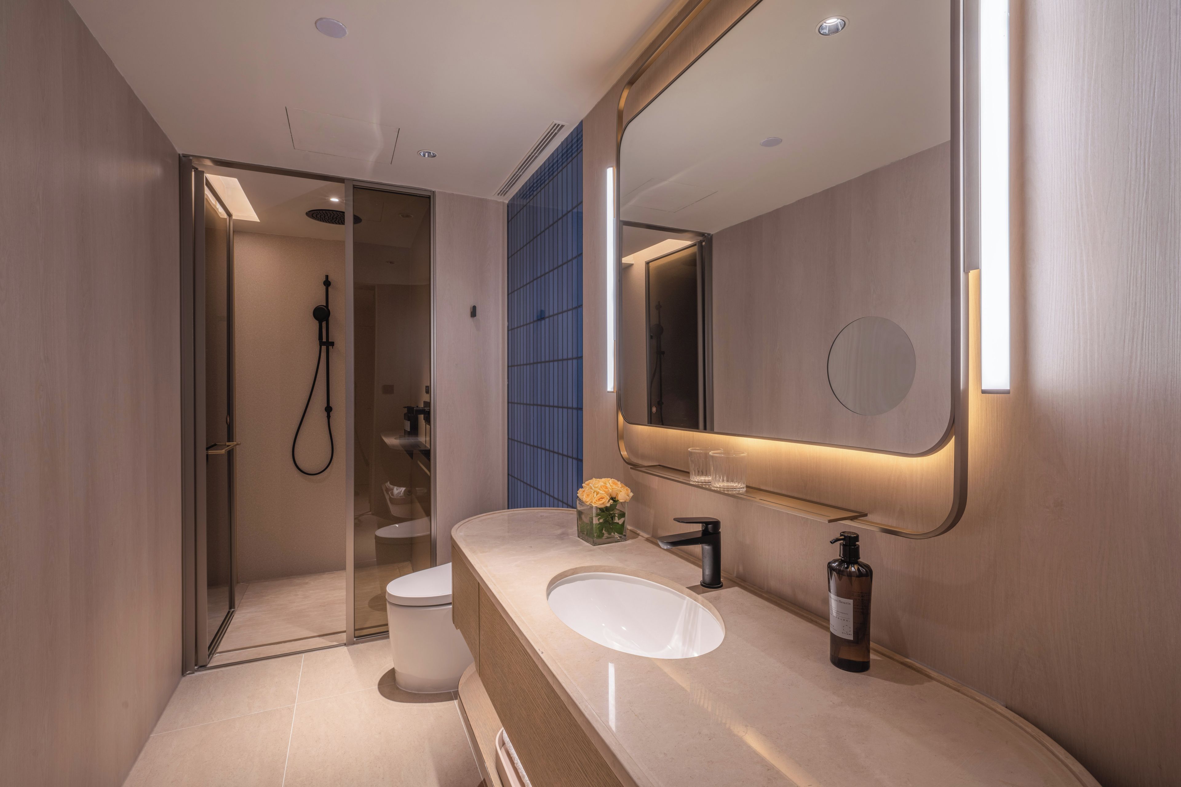 Un baño moderno con un espejo grande, un lavabo y una zona de ducha.