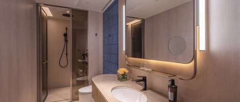 Un baño moderno con un espejo grande, un lavabo y una zona de ducha.