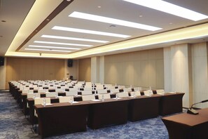 Un salón de conferencias con filas de mesas y sillas, equipado con tarjetas de identificación y botellas de agua.