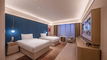 Habitación de hotel con dos camas, un televisor, un escritorio y una mesita.