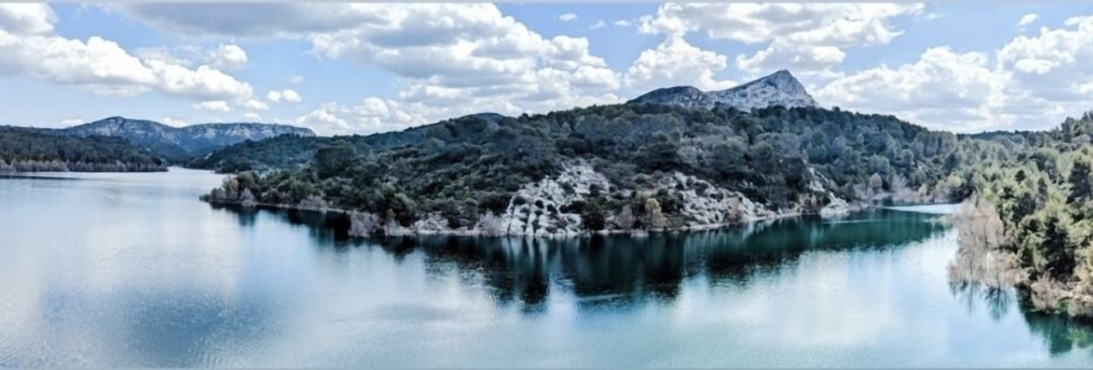 Un lago tranquilo con una montaña al fondo y un cielo despejado.