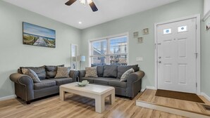 A living room with two sofas, a coffee table, a ceiling fan, a door, and a window with blinds. - Bayview Oasis in the Heart of Seaside Heights (Seaside Heights)