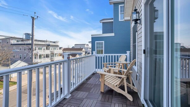 A balcony with wooden chairs and a white railing, overlooking a residential area. - Bayview Oasis in the Heart of Seaside Heights (Seaside Heights)