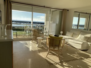Un vaste salon doté d’une grande porte-fenêtre coulissante donnant sur un balcon avec vue sur les bateaux et une marina.