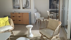 Un salon moderne avec un canapé, des fauteuils, une petite table blanche, un meuble en bois et des œuvres d’art accrochées aux murs.
