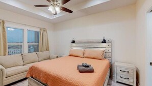 A bedroom with a bed, a nightstand, a ceiling fan, and a window with curtains.