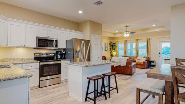 A modern kitchen with white cabinets, stainless steel appliances, and a central island with stools.