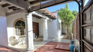 A covered outdoor area with a tiled floor, white columns, a pergola, and a blue gas cylinder. - Stylish Getaway with Private Pool, Fire Pit & Xbox – Walk to the Beach! (Puerto Peñasco)