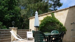 Eine Terrasse im Freien mit einem runden Tisch, Stühlen, einem Klappstuhl und einer Lampe.