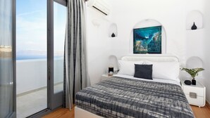 A bedroom with a large bed, a view of the sea, and a painting on the wall. - Serenity View Villa with Caldera view, heated pool & hot tub in private garden (Thira - Santorini)