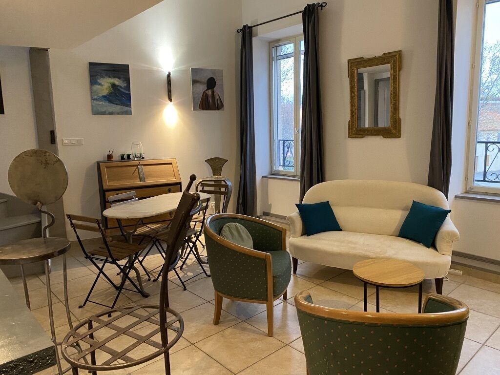 Ein Wohnzimmer mit einer Couch, Sesseln, einem Esstisch und einem kleinen Beistelltisch.