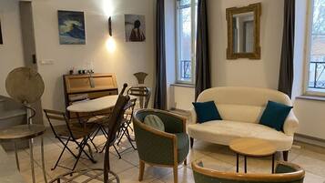 Ein Wohnzimmer mit einer Couch, Sesseln, einem Esstisch und einem kleinen Beistelltisch.
