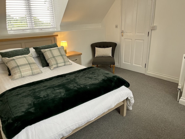 A bedroom with a bed, a nightstand, a chair, and a door.