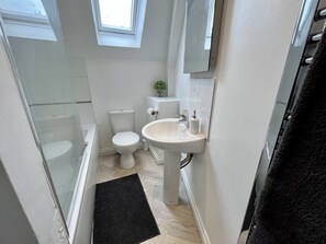 A compact bathroom with a toilet, sink, and shower. - Detached Cottage with private garden and hot tub. (St Austell)