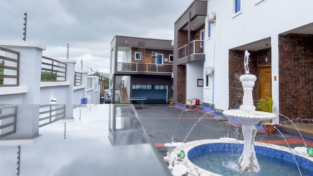 A modern building with a rooftop pool and a fountain. - Meraki Apartments (Akure)